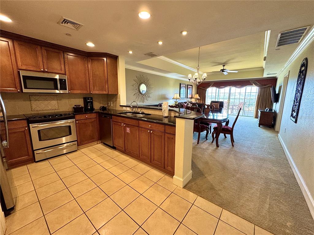 1350 Centre Ct Ridge Drive, Unit 401 Reunion, FL 34747 - Photo 11 of 32 a kitchen with stainless steel appliances granite countertop a stove top oven a sink a dining table and chairs