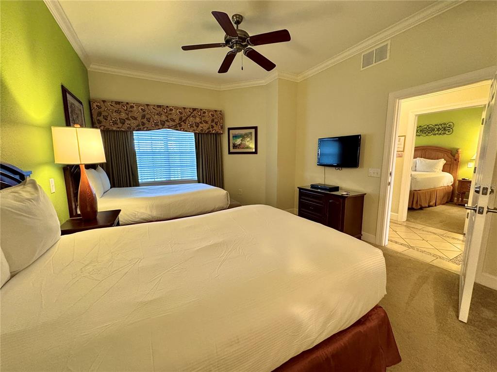 1350 Centre Ct Ridge Drive, Unit 401 Reunion, FL 34747 - Photo 7 of 32 a bedroom with a large bed a flat tv screen and a chandelier