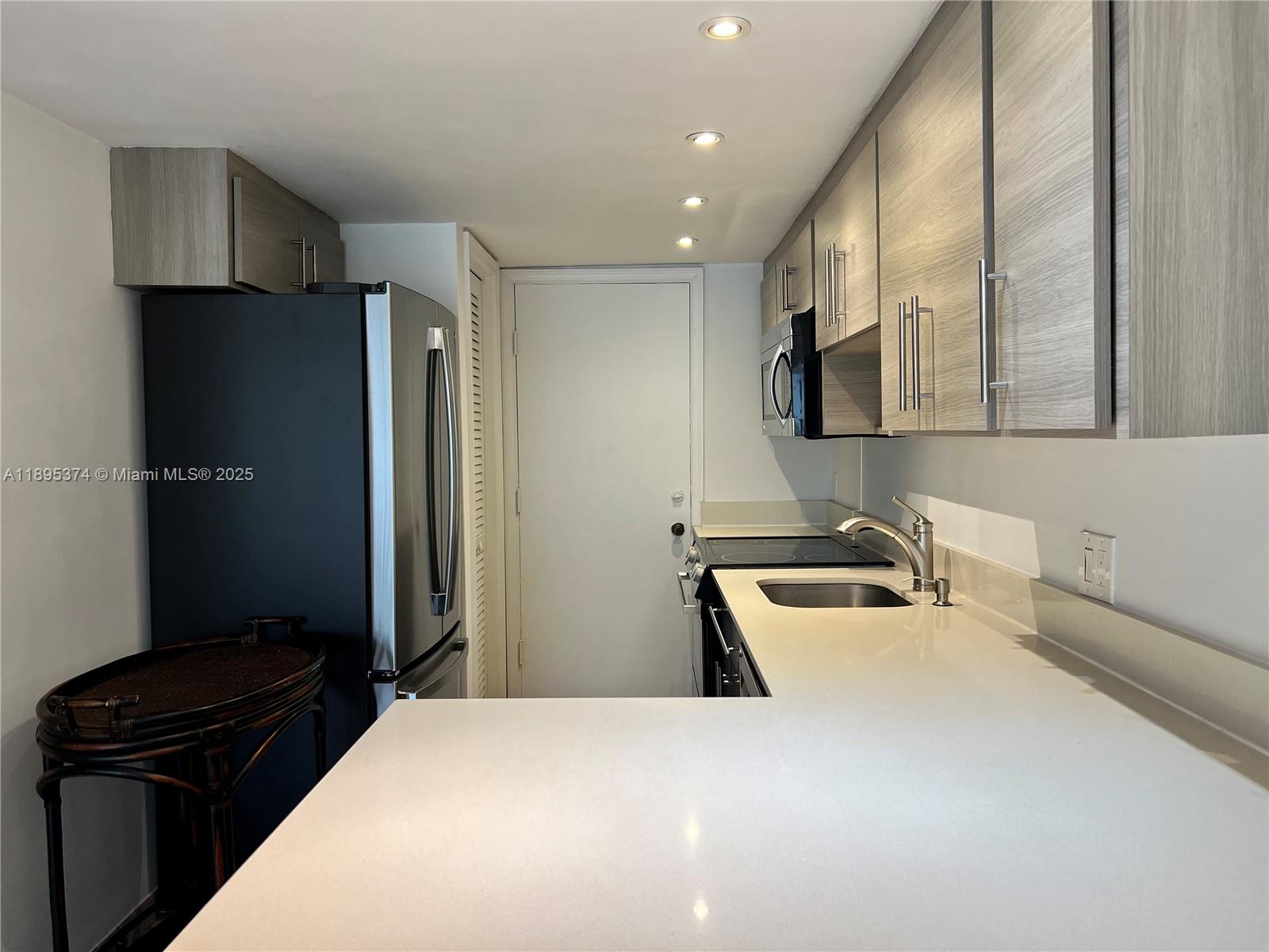 555 Crandon Boulevard, Unit 53 Key Biscayne, FL 33149 - Photo 15 of 33 a kitchen with a refrigerator and a sink