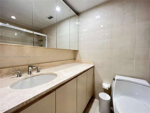 a bathroom with a granite countertop sink a toilet and a mirror