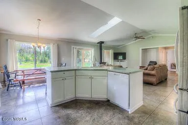 a room with kitchen island granite countertop lots of white furniture a sink and a large window