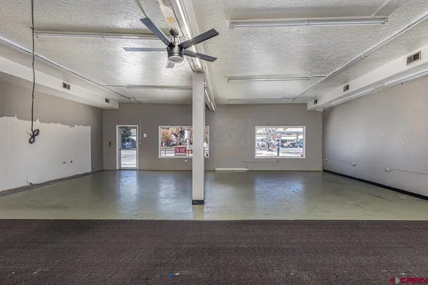 an empty room with windows and ceiling fan
