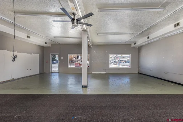 an empty room with windows and ceiling fan