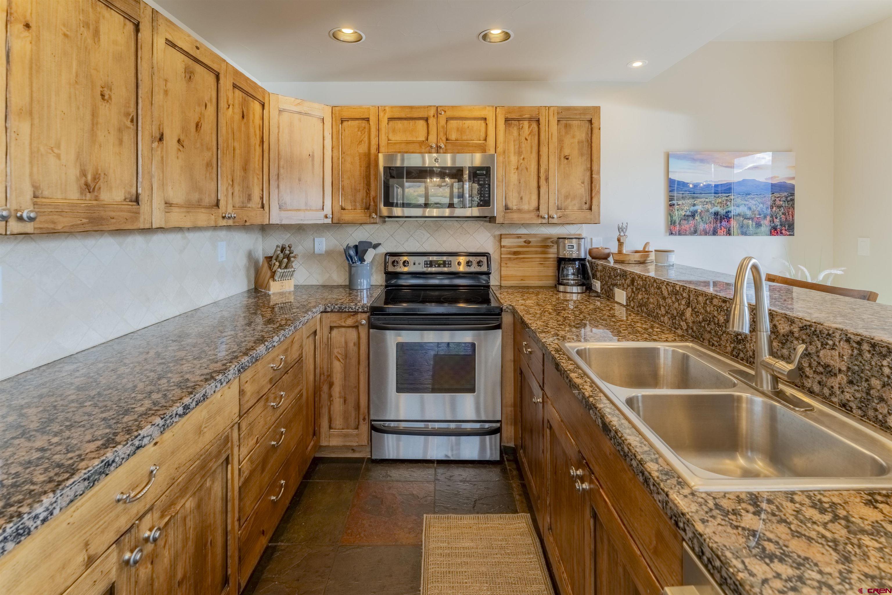 9 Hunter Hill Road, Unit 301 Crested Butte, CO 81225 - Photo 13 of 44 a kitchen with granite countertop a stove sink and cabinets