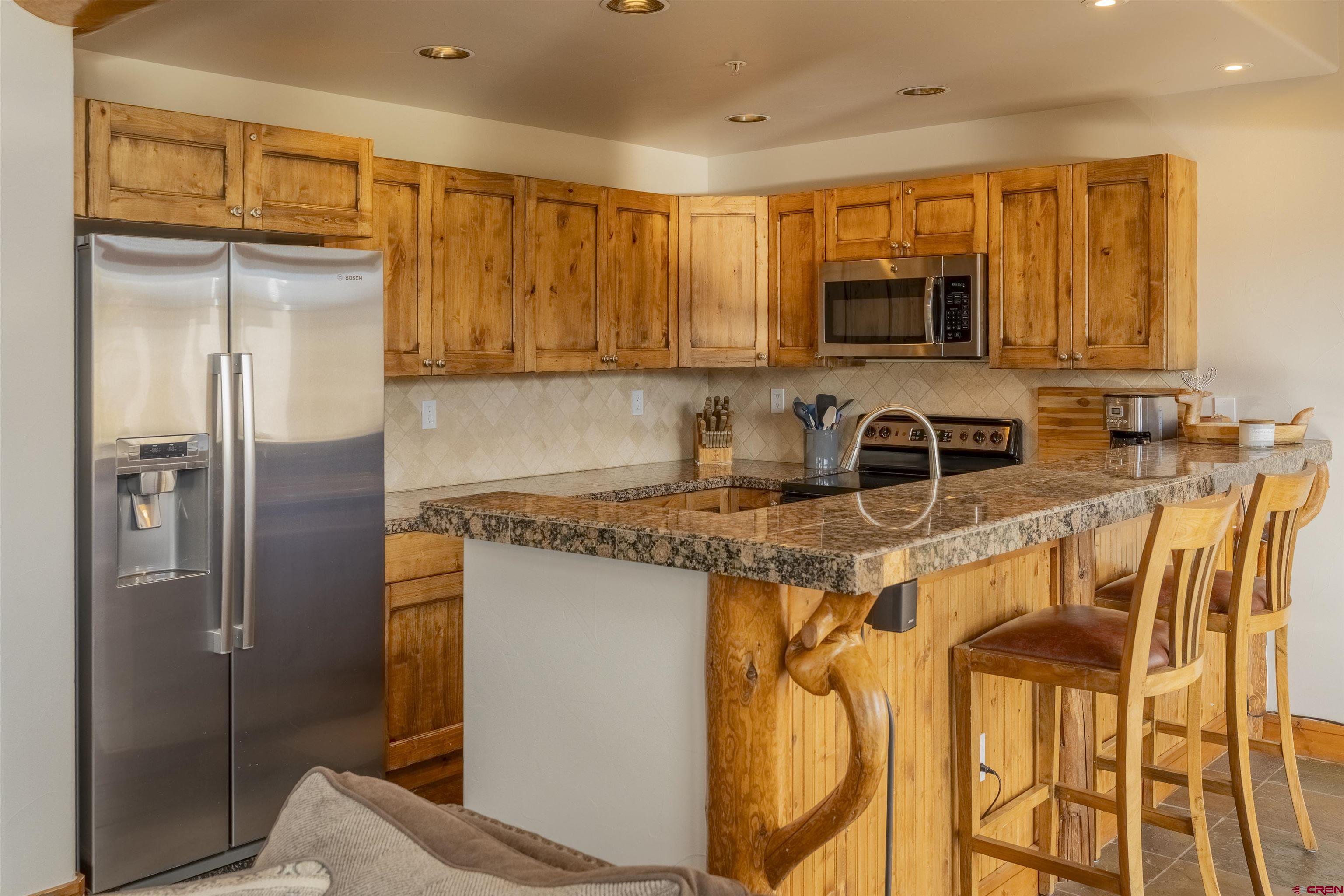 9 Hunter Hill Road, Unit 301 Crested Butte, CO 81225 - Photo 14 of 44 a kitchen with stainless steel appliances granite countertop a refrigerator a stove and a sink with wooden floor