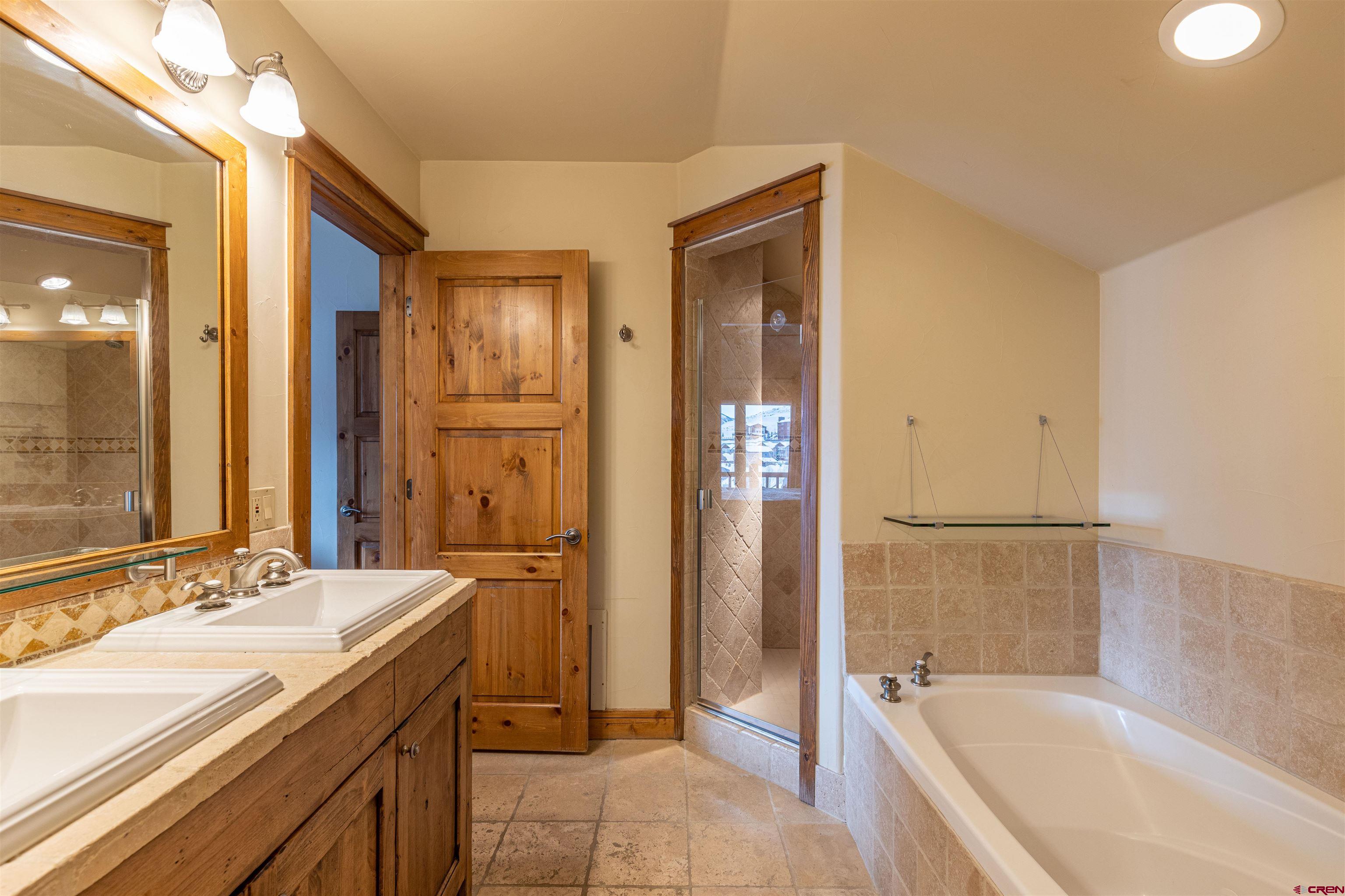 9 Hunter Hill Road, Unit 301 Crested Butte, CO 81225 - Photo 26 of 44 a spacious bathroom with a granite countertop tub sink a mirror and a shower