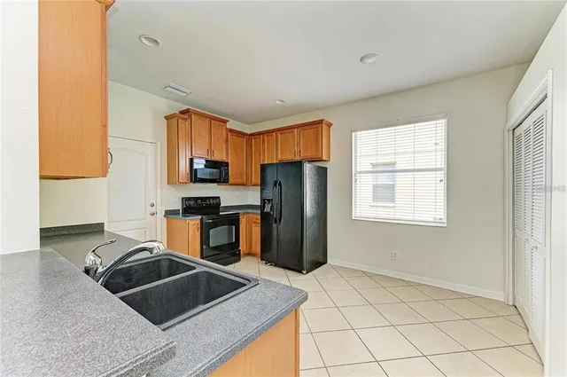 a kitchen with granite countertop a refrigerator and a stove top oven