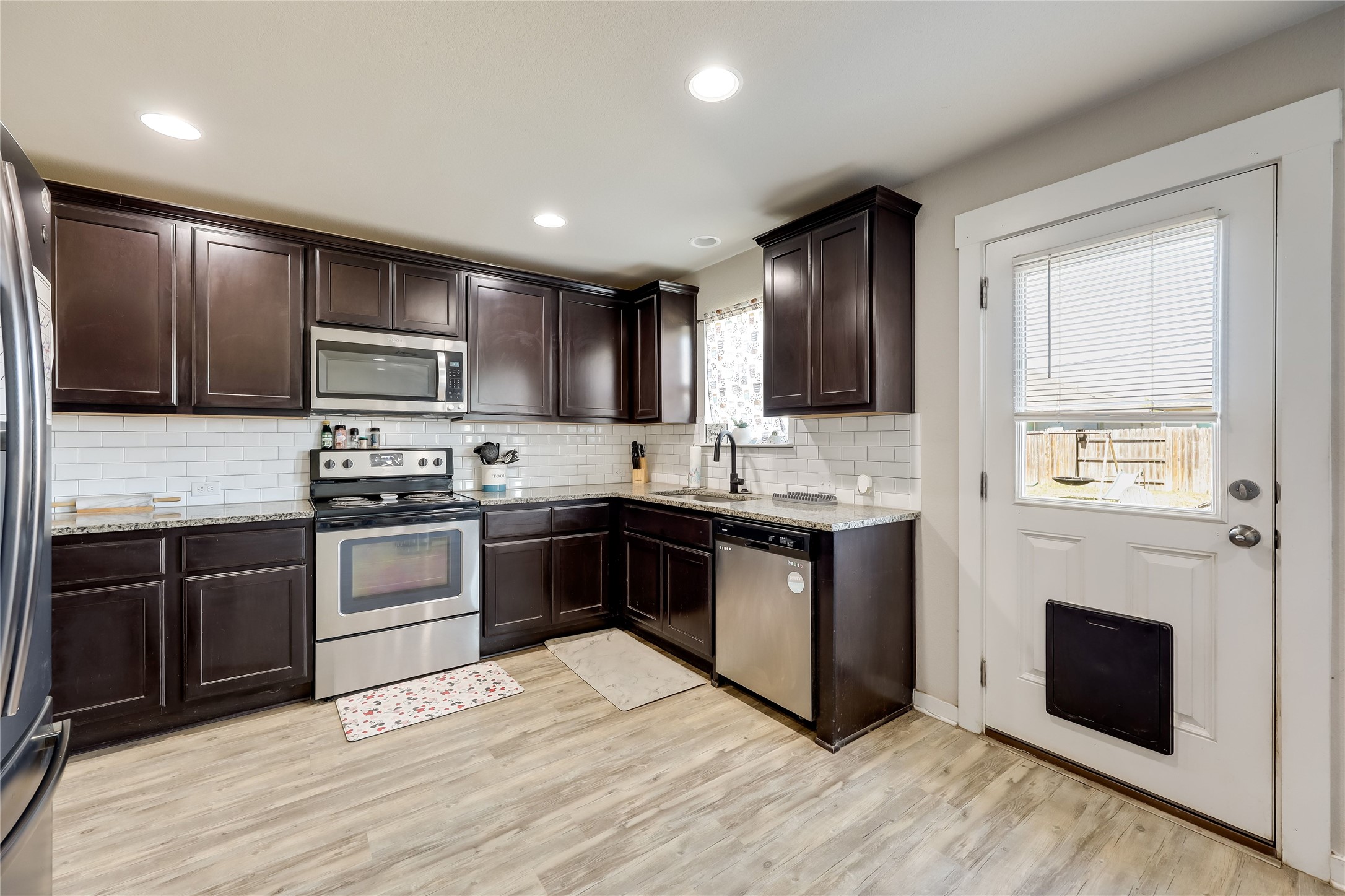 249 Trellis Boulevard Leander, TX 78641 - Photo 8 of 18 a kitchen with kitchen island granite countertop a stove top oven a sink dishwasher a refrigerator and a microwave oven with wooden floor