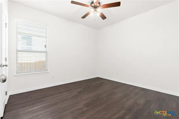an empty room with wooden floor fan and windows