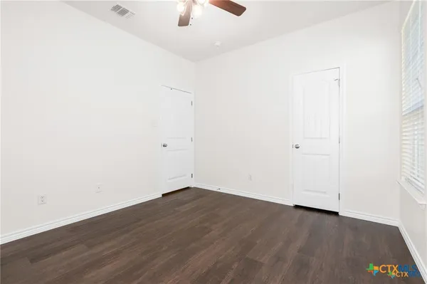 an empty room with wooden floor and fan