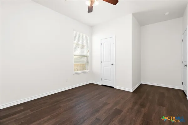 an empty room with wooden floor cabinet and windows