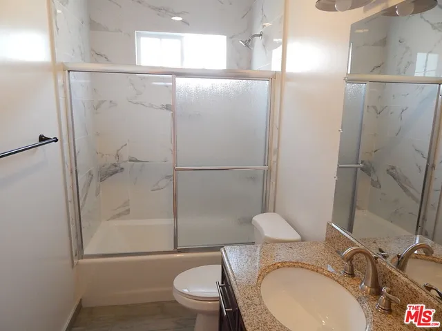 a bathroom with a granite countertop sink toilet and shower