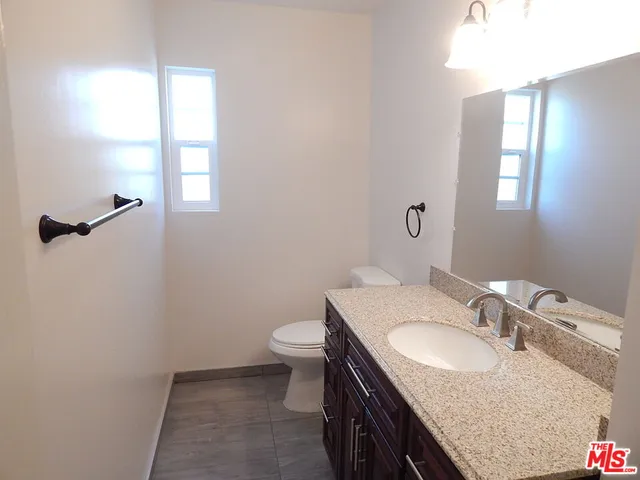 a bathroom with a granite countertop sink a toilet and a mirror