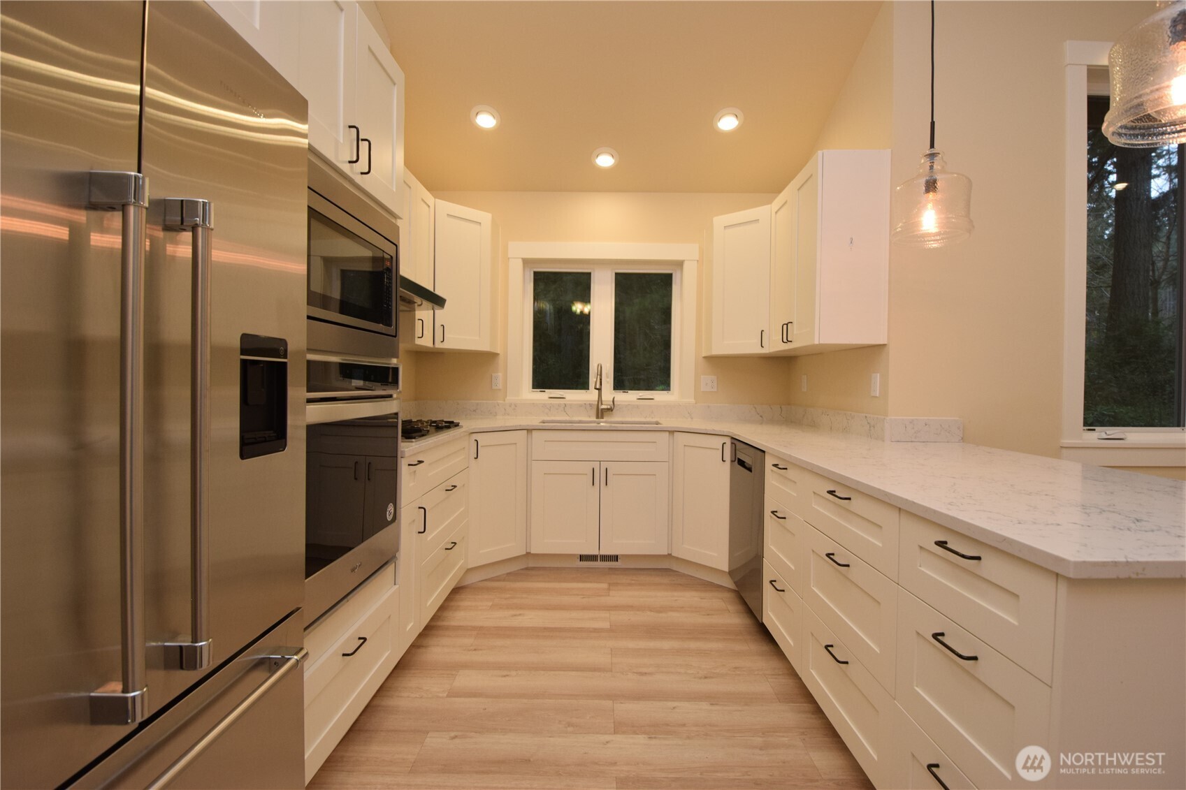 15915 Nesika Bay Road Northeast Poulsbo, WA 98370 - Photo 14 of 40 a kitchen with granite countertop a refrigerator and white cabinets