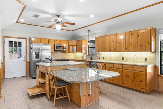 a kitchen with granite countertop a table chairs sink and cabinets