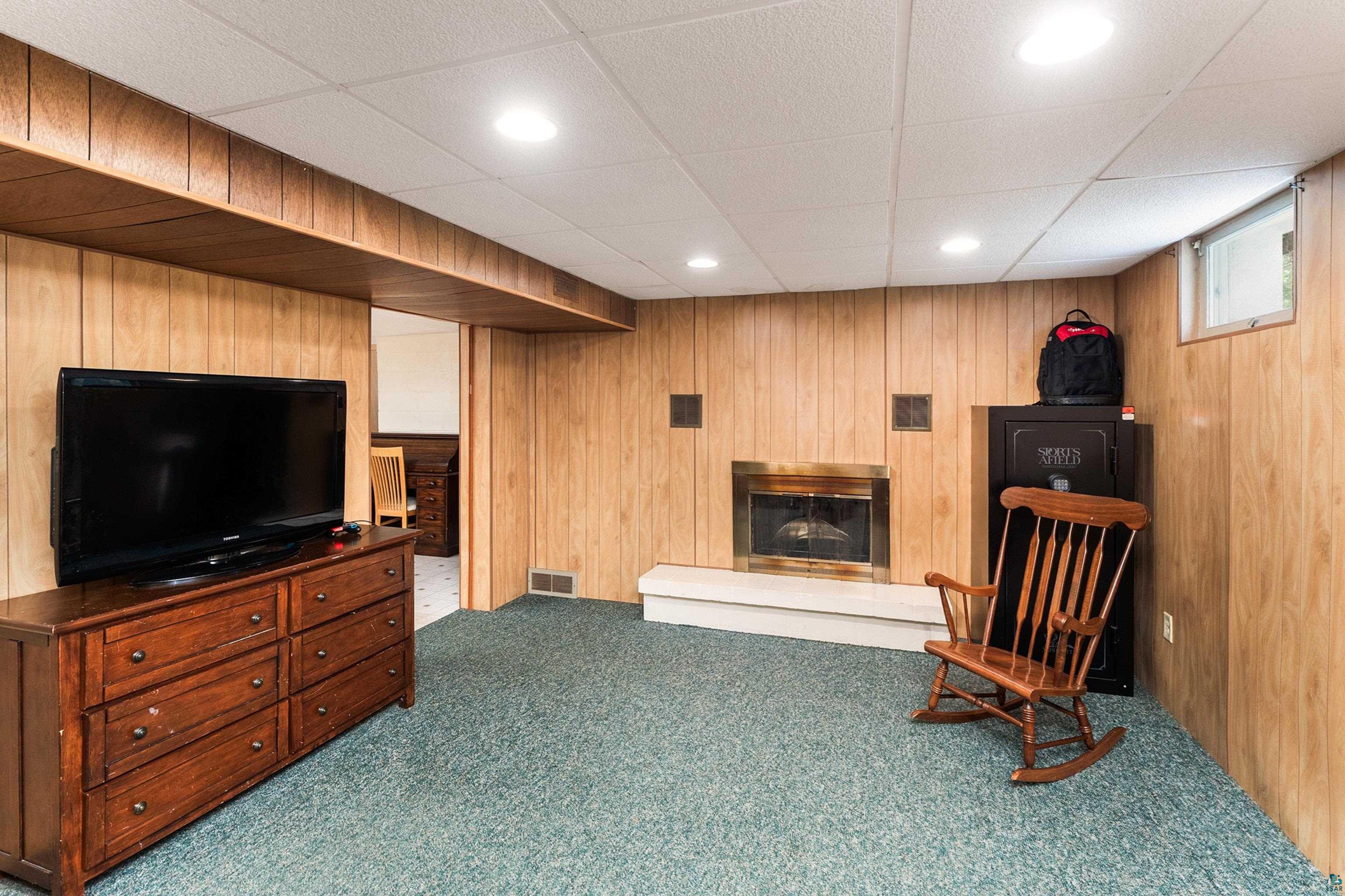 4808 Midway Road Duluth, MN 55811 - Photo 32 of 57 Finished space featuring wood paneling, a recessed fireplace with a hearth, a drop ceiling with recessed lighting, and a window