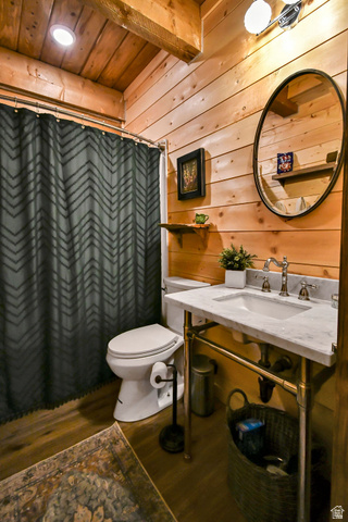544 East 600 North, Unit 1 Joseph, UT 84739 - Photo 28 of 65 Bathroom featuring wood plank walls, exposed wood ceiling beams, wood-finish flooring, a white vanity with a marble-look countertop, and a circular mirror