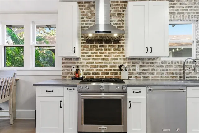 a kitchen with granite countertop a sink stainless steel appliances and a window