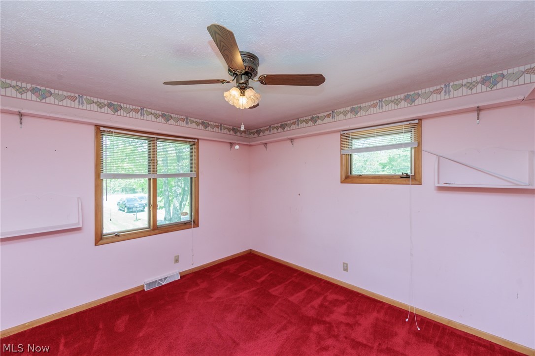 2170 Norton Road Stow, OH 44224 - Photo 39 of 48 Room featuring red carpeting, two windows with wood-finish trim, and a ceiling fan with integrated lighting