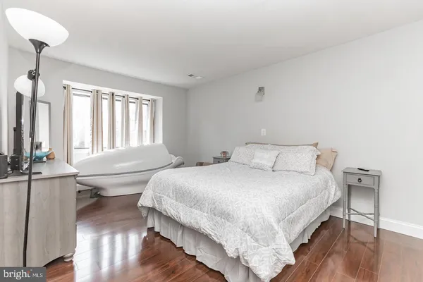 a bedroom with a bed a large window and wooden floor
