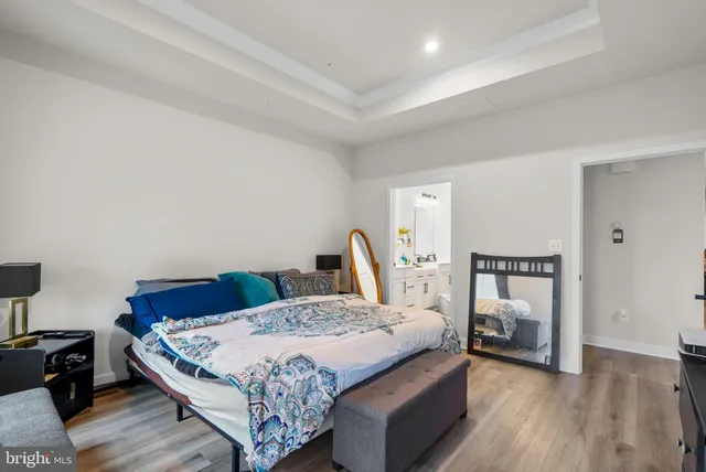 a bedroom with a bed a couch and a flat tv screen on the dresser