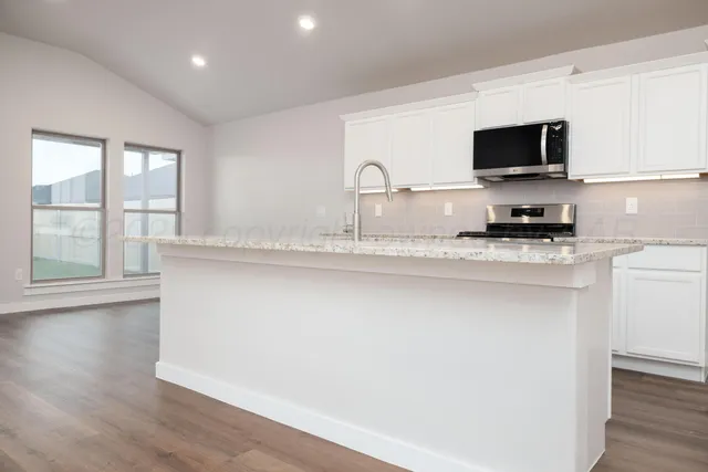 a kitchen with granite countertop a sink and a stove top oven