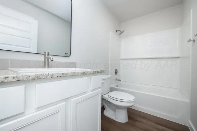a bathroom with a granite countertop toilet sink and a mirror