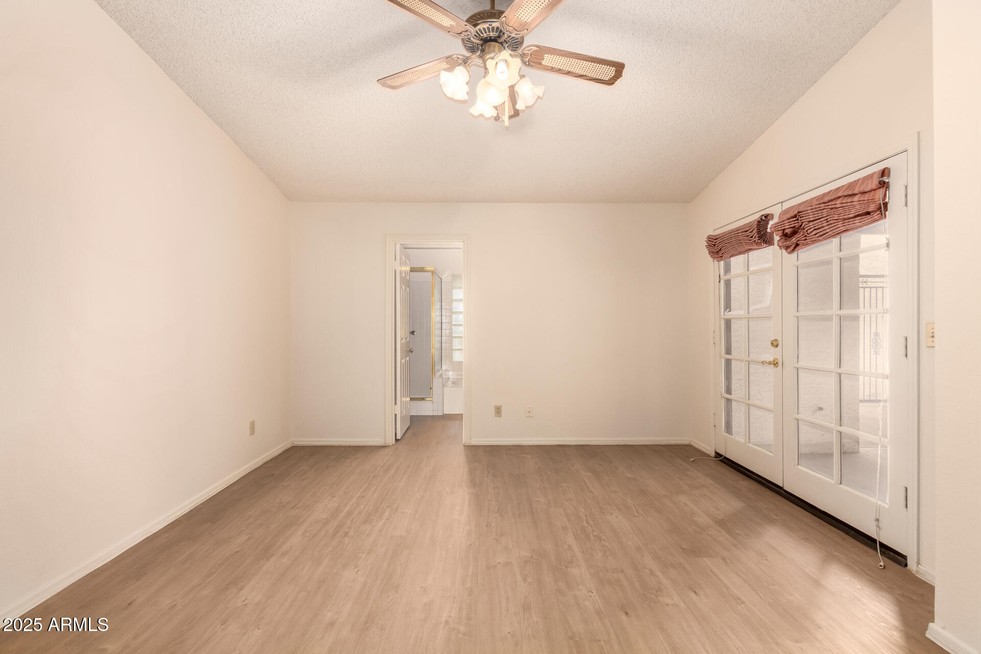 2059 East Brown Road, Unit 30 Mesa, AZ 85213 - Photo 10 of 24 an empty room with a ceiling fan and wooden floor