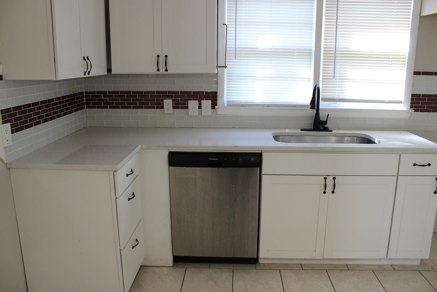 1673 South White Station Road Memphis, TN 38117 - Photo 8 of 17 Kitchen with stainless steel dishwasher, white cabinetry, decorative backsplash, and light stone counters
