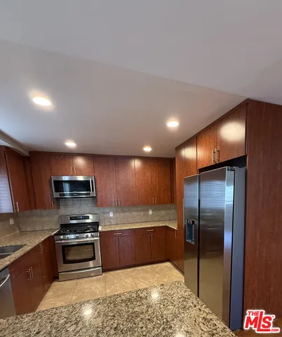 a kitchen with stainless steel appliances wooden cabinets a sink and a stove