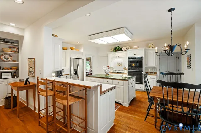 a kitchen with stainless steel appliances kitchen island granite countertop a table chairs and a refrigerator