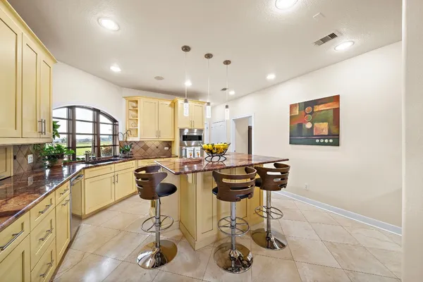 a kitchen with stainless steel appliances granite countertop a refrigerator and a stove top oven
