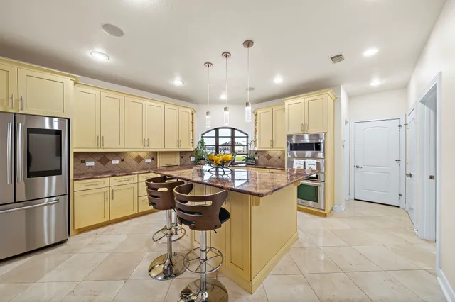 a kitchen with stainless steel appliances granite countertop a refrigerator and a stove top oven