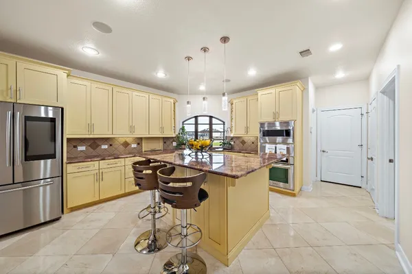 a kitchen with stainless steel appliances kitchen island granite countertop a stove top oven sink and cabinets