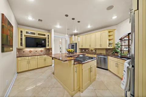 a kitchen with stainless steel appliances granite countertop a stove refrigerator and chairs