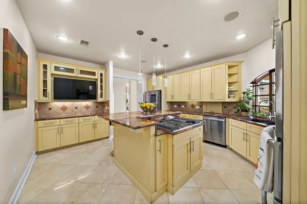 a kitchen with stainless steel appliances granite countertop a stove refrigerator and chairs
