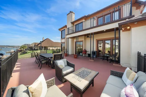 a view of a patio with couches table and chairs under an umbrella
