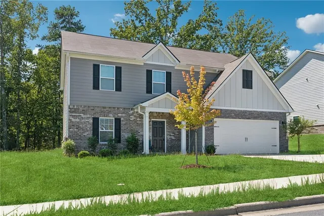 a view of a yard in front of a house with plants and large tree