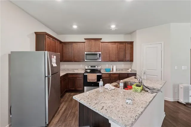 a kitchen with stainless steel appliances granite countertop a refrigerator sink stove microwave and cabinets