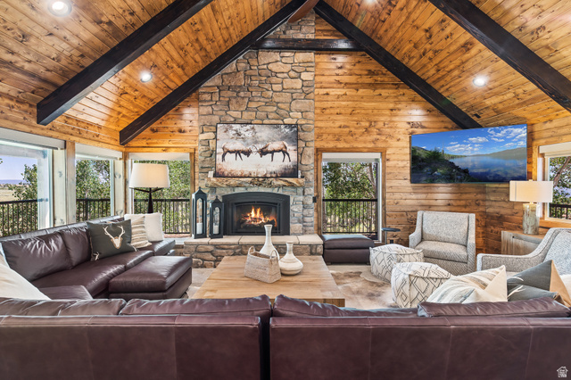 2031 South Quakie Road Koosharem, UT 84744 - Photo 7 of 33 Vaulted wood-paneled ceiling with exposed beams, stone-clad fireplace, large windows, and a built-in entertainment area
