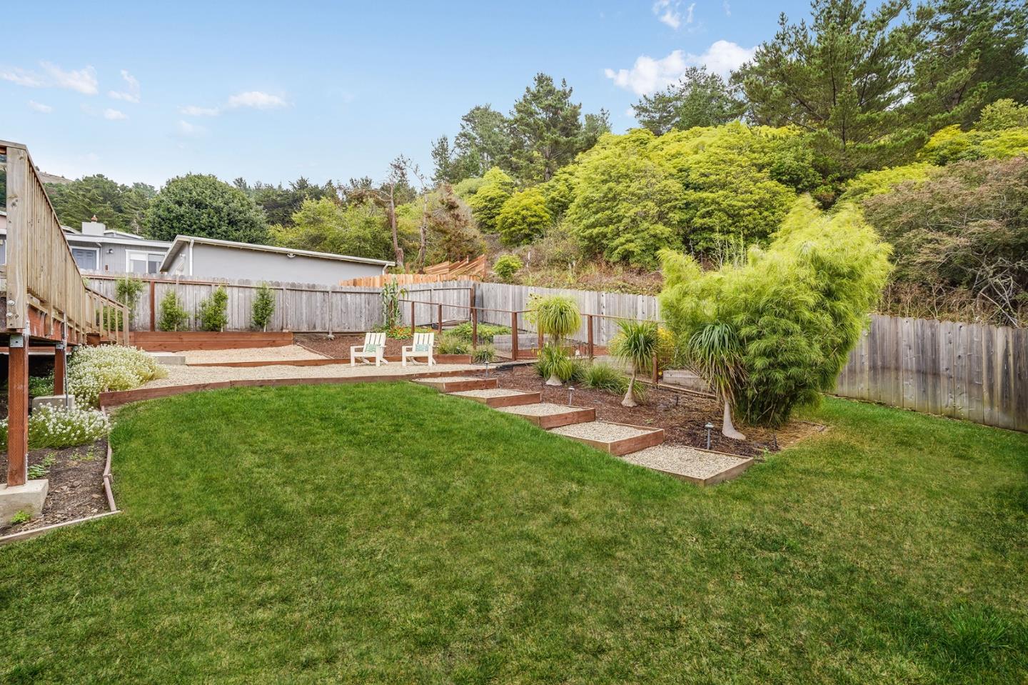 646 Brighton Road Pacifica, CA 94044 - Photo 21 of 26 a view of a patio with table and chairs under an umbrella with large trees