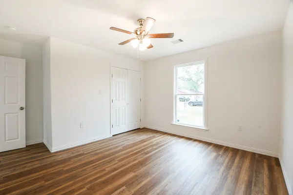 an empty room with wooden floor and windows