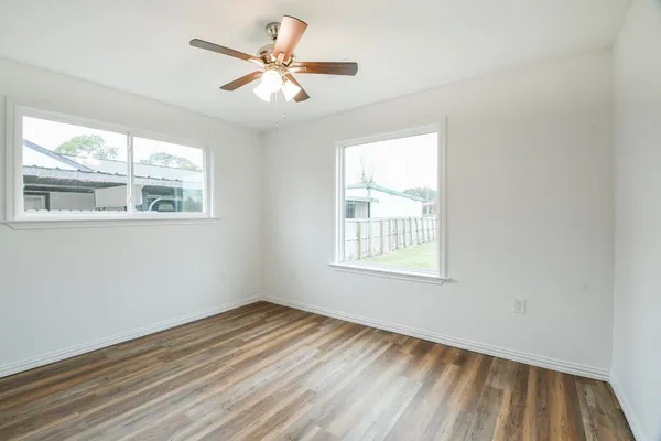 an empty room with wooden floor and windows