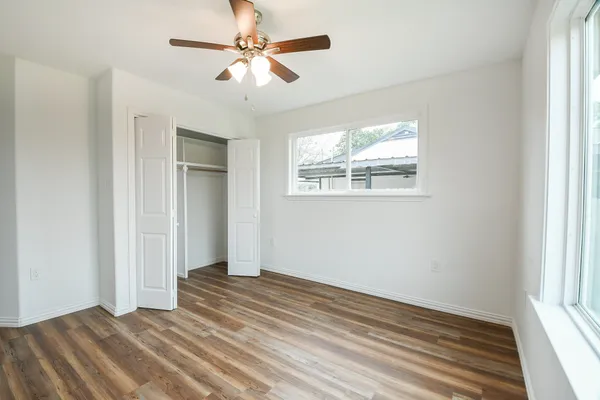 a view of empty room with wooden floor and fan