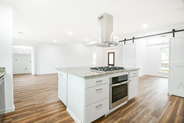 a kitchen with a stove and wooden floor