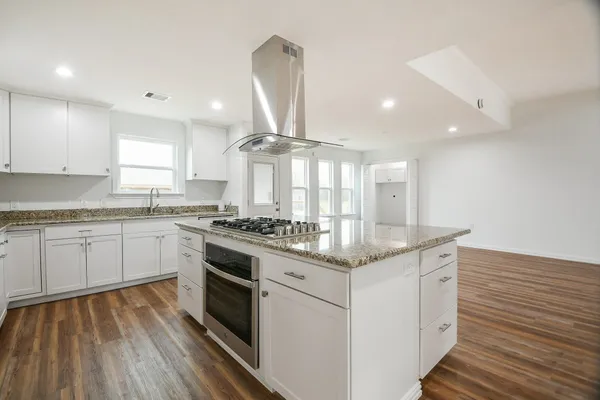 a kitchen with stainless steel appliances granite countertop a stove and white cabinets