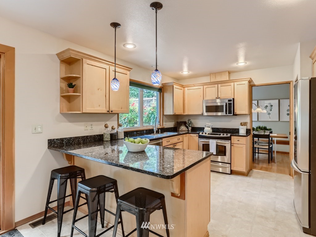 23630 3rd Place West Bothell, WA 98021 - Photo 11 of 28 a kitchen with stainless steel appliances granite countertop a stove top oven a sink a dining table and chairs