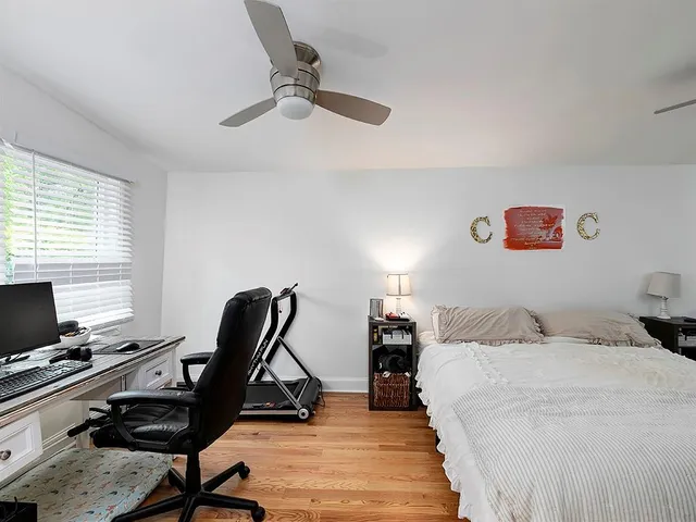a bedroom with a bed and a computer on a desk next to a window
