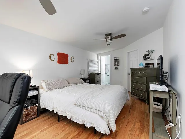 a bedroom with a bed a dresser and book shelfs