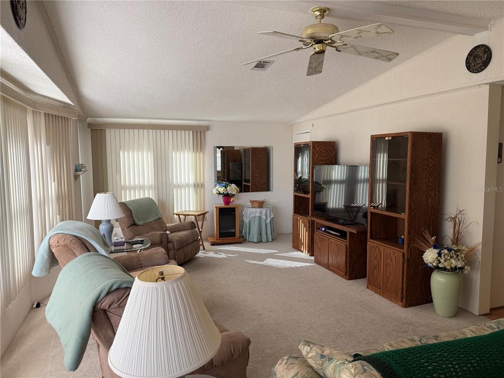 105 Cypress Road Wildwood, FL 34785 - Photo 9 of 26 a living room with furniture a chandelier and a flat screen tv